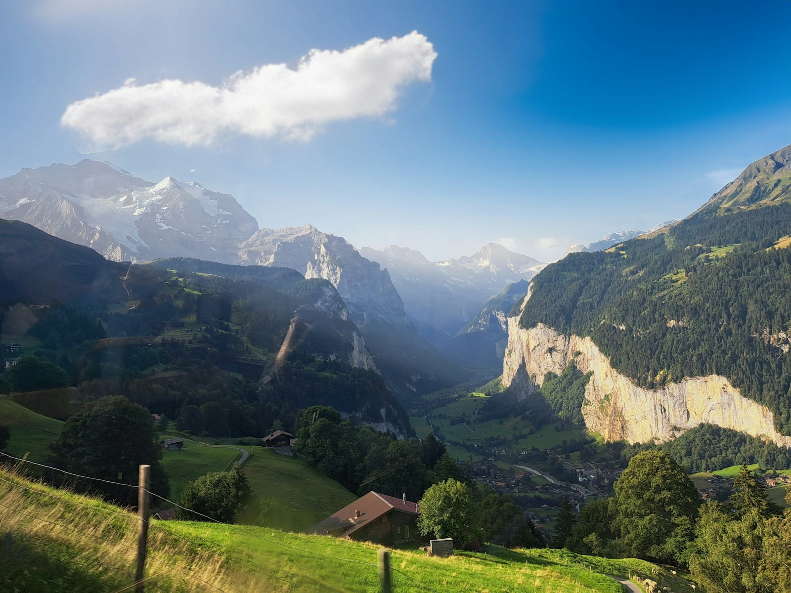 A sunny green valley with mountains in the background
