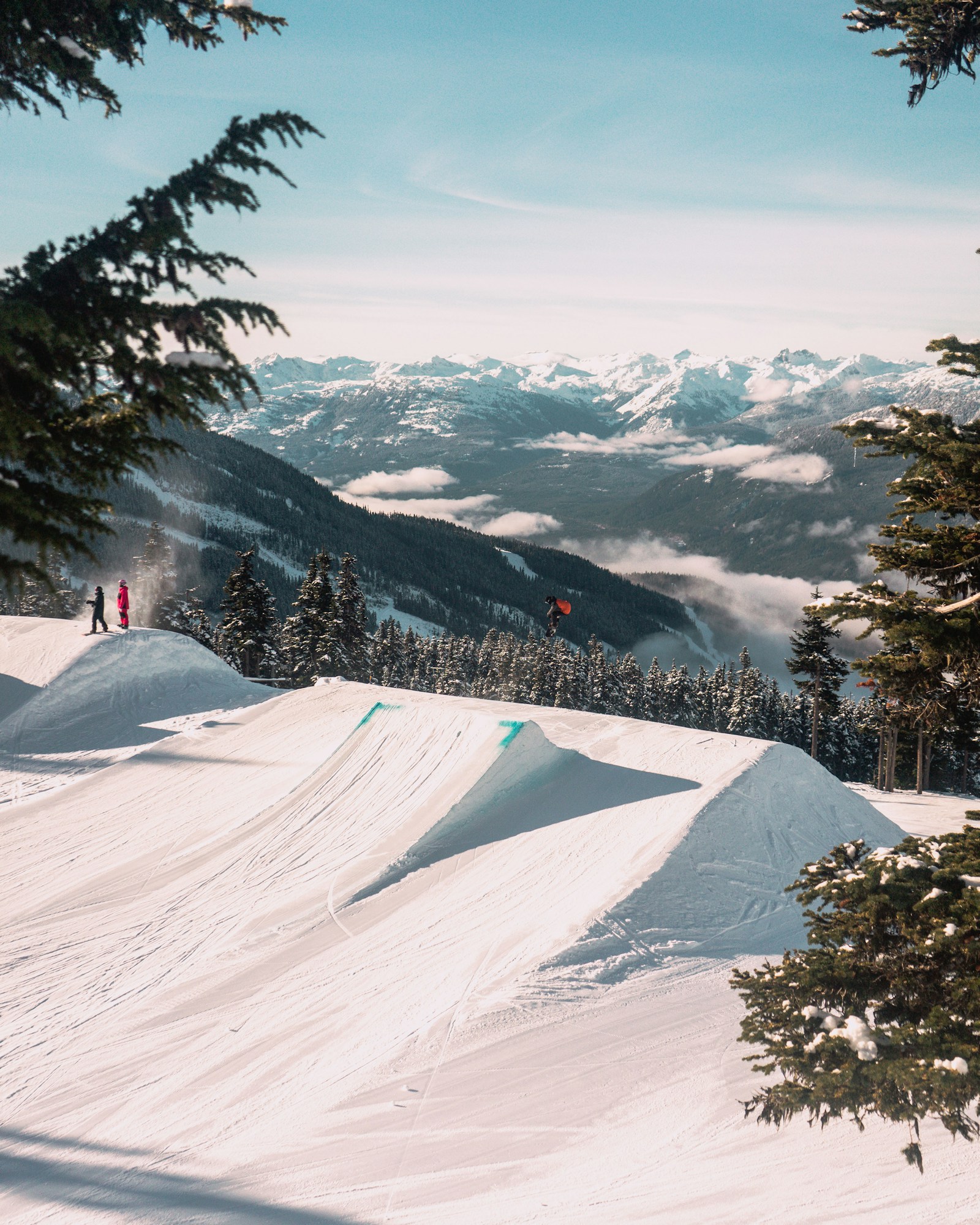 A sunny ski resort terrain park with snowy mountains
