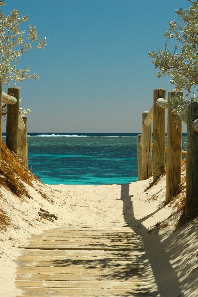 Boardwalk through the dunes to a turquoise sea